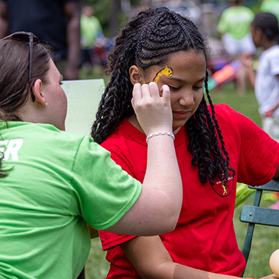 Young woman painting another young woman's face